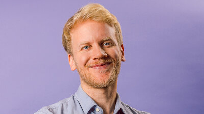 Foto von Florian Schwenkert, Gründer von KoRo, vor einem lila Hintergrund. 