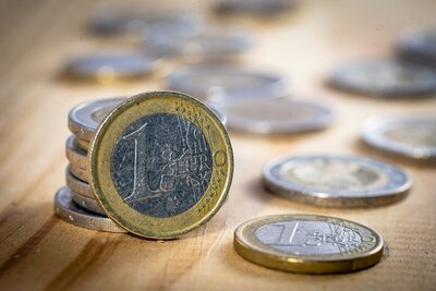 Nahaufnahme von Ein- und Zwei-Euromünzen auf einem Holztisch.