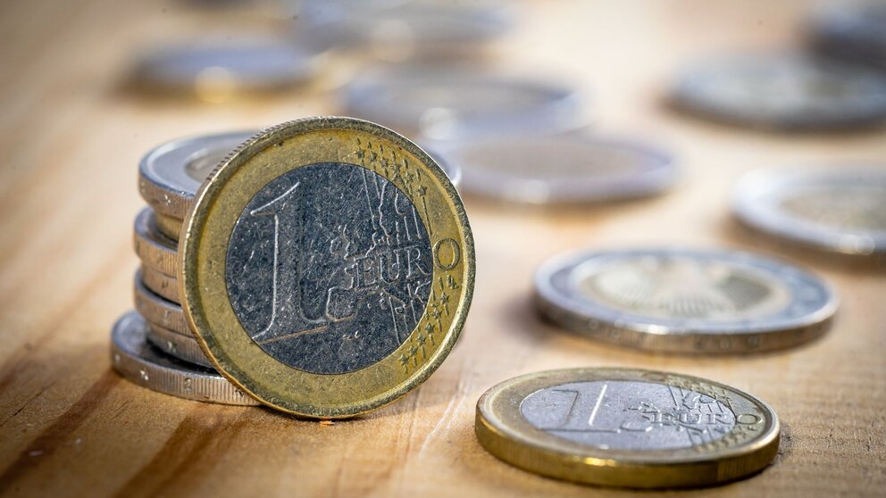 Nahaufnahme von Ein- und Zwei-Euromünzen auf einem Holztisch.