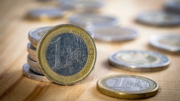 Nahaufnahme von Ein- und Zwei-Euromünzen auf einem Holztisch.