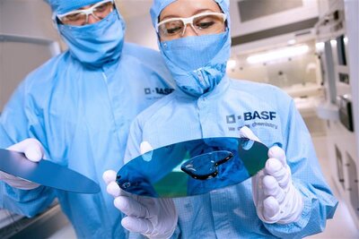 Zwei Personen in blauer Schutzkleidung schauen auf eine Disc.