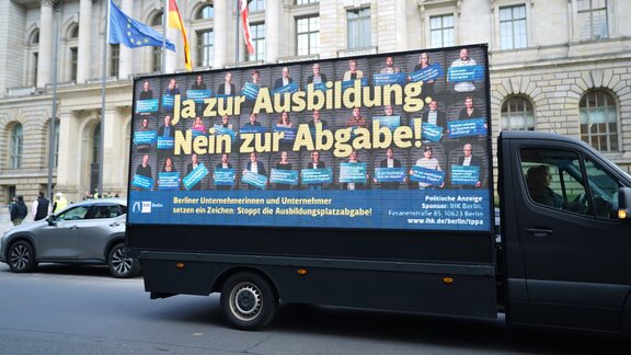 Ein Kleintransporter mit einem Plakat steht vor dem Berliner Abgeordnetenhaus.