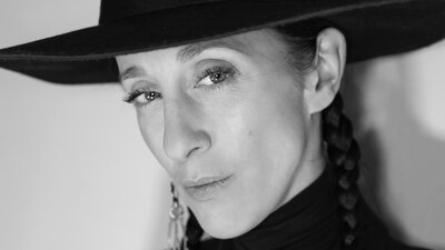 Schwarz-Weiß-Porträt einer Frau mit schwarzem Hut vor einer Wand. Es ist CEO und Designerin Esther Perbandt.