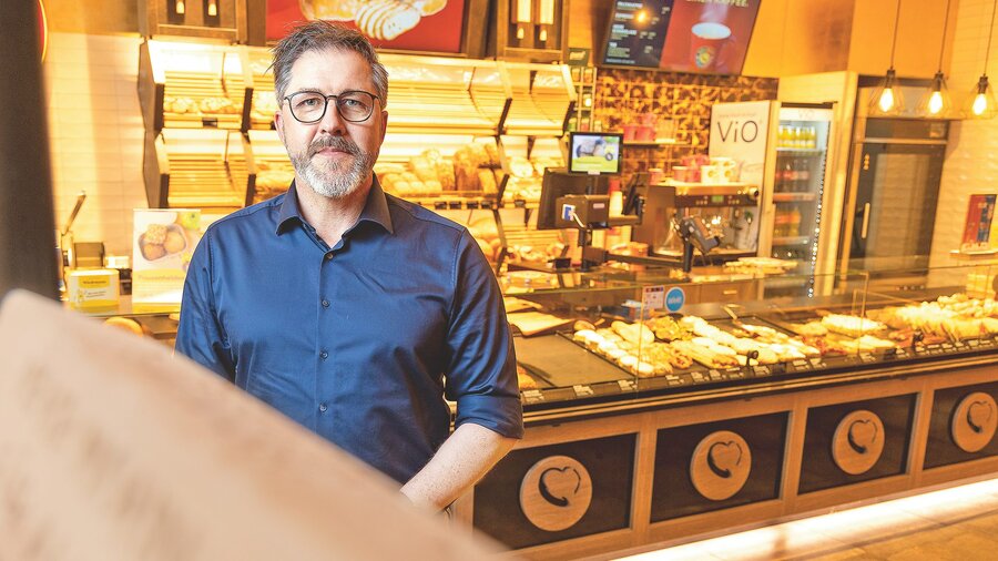 Auf dem Bild ist ein Mann in einer Bäckerei zu sehen.