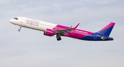 Zu sehen ist ein Flugzeug der Airline Wizz Air, welches vor bewölktem Himmel fotografiert wurde.