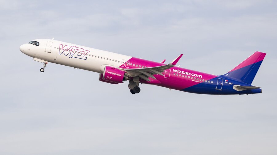 Zu sehen ist ein Flugzeug der Airline Wizz Air, welches vor bewölktem Himmel fotografiert wurde.