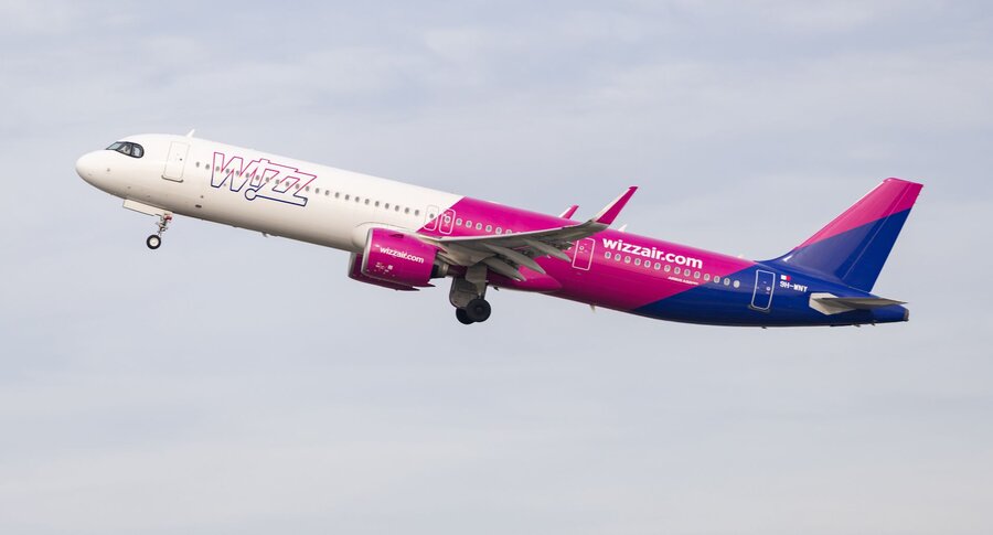 Zu sehen ist ein Flugzeug der Airline Wizz Air, welches vor bewölktem Himmel fotografiert wurde.
