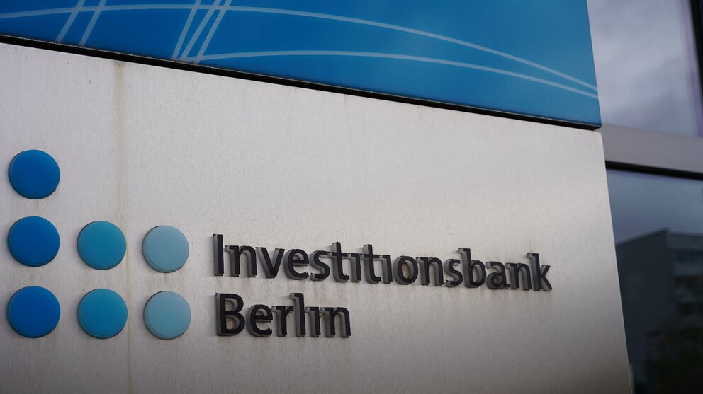 Zu sehen ist ein Logo bestehend aus sieben blauen Punkten und dem Schriftzuge Investitionsbank Berlin daneben. Es handelt sich um das Logo der Investitionsbank Berlin.