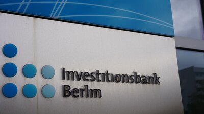 Zu sehen ist ein Logo bestehend aus sieben blauen Punkten und dem Schriftzuge Investitionsbank Berlin daneben. Es handelt sich um das Logo der Investitionsbank Berlin.