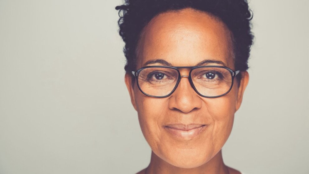 Zu sehen ist der Kopf einer mittelalten Frau mit schwarzen Haaren und Brille. Sie schaut freundlich, es handelt sich um die Medienexpertin Mo Asumang.