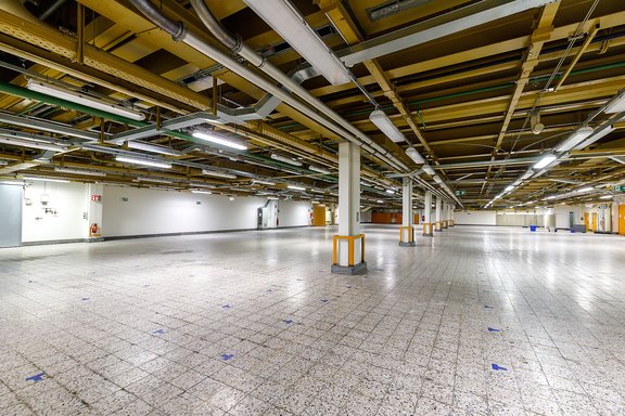 Leerer, großer Industrie- oder Lagerraum mit weißen Säulen und sichtbaren Rohrleitungen an der Decke