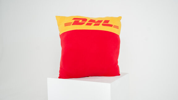 Ein Kissen aus alter DHL-Bekleidung in den Farben Gelb und Rot. 