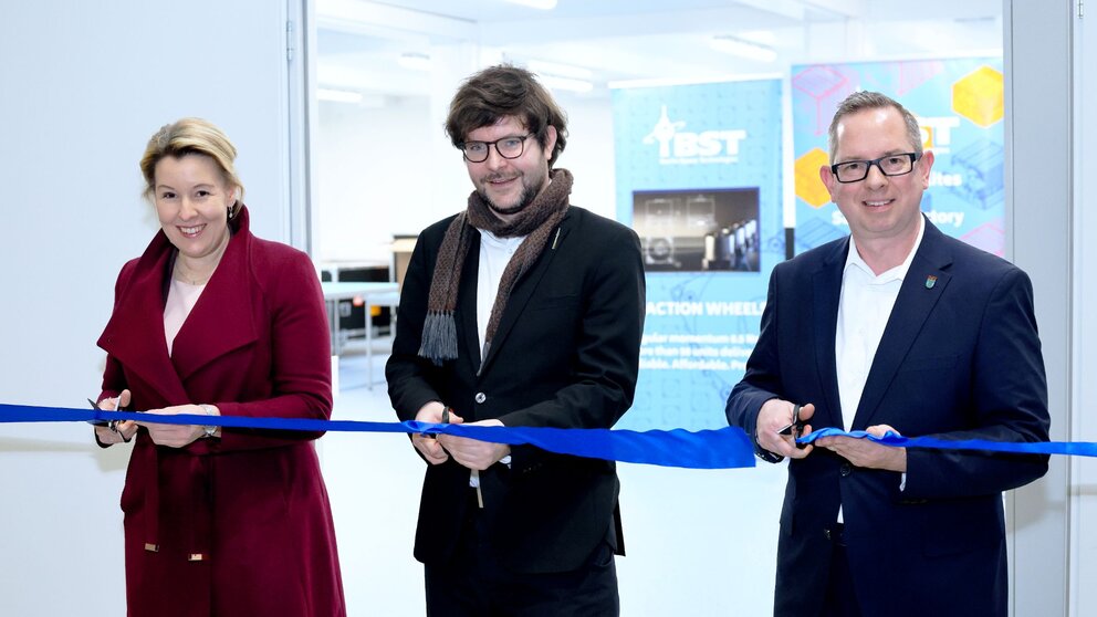 Drei Menschen schneiden ein blaues Band durch, es sind Franziska Giffey, Wirtschaftssenatorin, mit Tom Segert, CEO Berlin Space Technologies, und Oliver Igel, Bezirksbürgermeister von Treptow-Köpenick