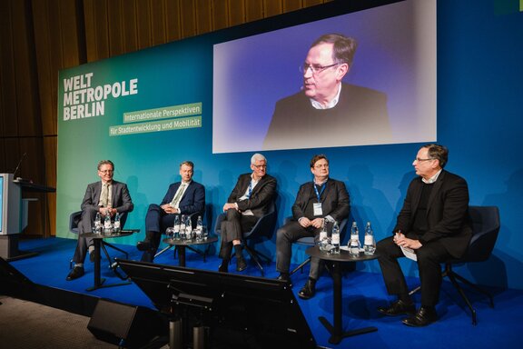 Fünf Personen unterhalten sich sitzend auf einer Bühne vor Publikum.