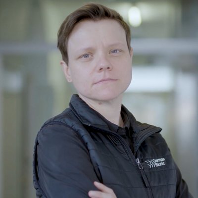 Eine Frau, die in einem Flur mit verschränktem Armen steht und nach vorne blickt. 