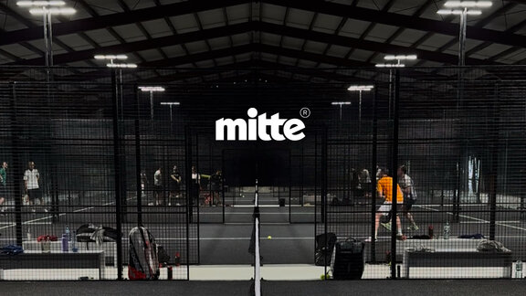 Mehrere Menschen spielen in einer Halle Padel