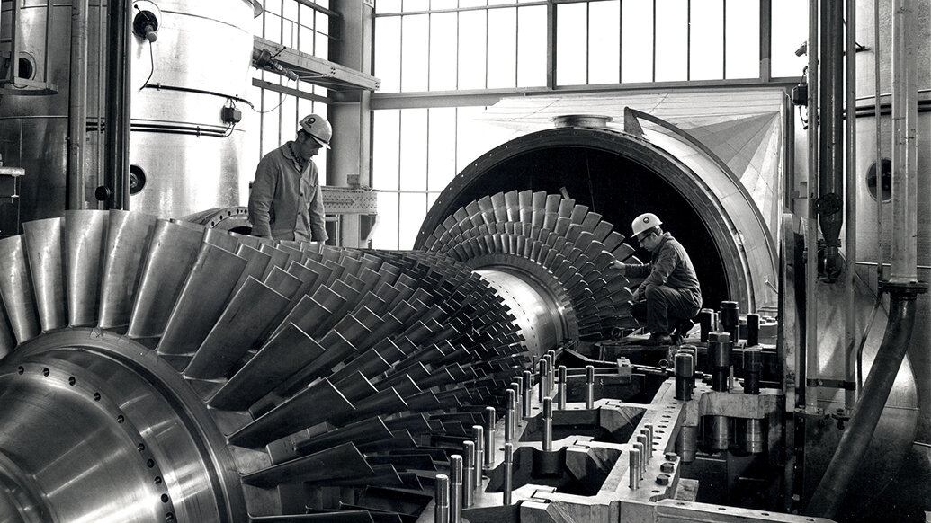 Zwei Arbeiter an einer Gasturbine. 