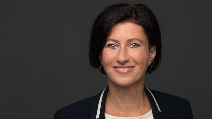 Zu sehen ist eine Frau mit mittellangen dunklen Haaren, die freundlich in die Kamera schaut. Es handelt sich um Jana Greiser.