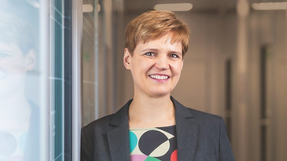 Auf dem Bild ist eine rotblond gefärbte Frau mit dunkelblauem Jackett und farbiger Bluse zu sehen.