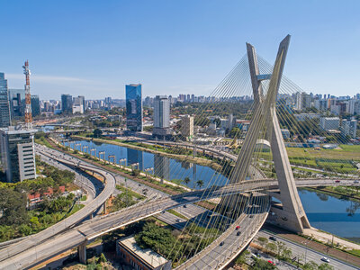 Luftaufnahme der Estaiada-Brücke in São Paulo mit ihren kreuzenden Straßen und dem Fluss Rio Pinheiros, umgeben von modernen Hochhäusern und breiten Verkehrsachsen bei klarem Himmel.