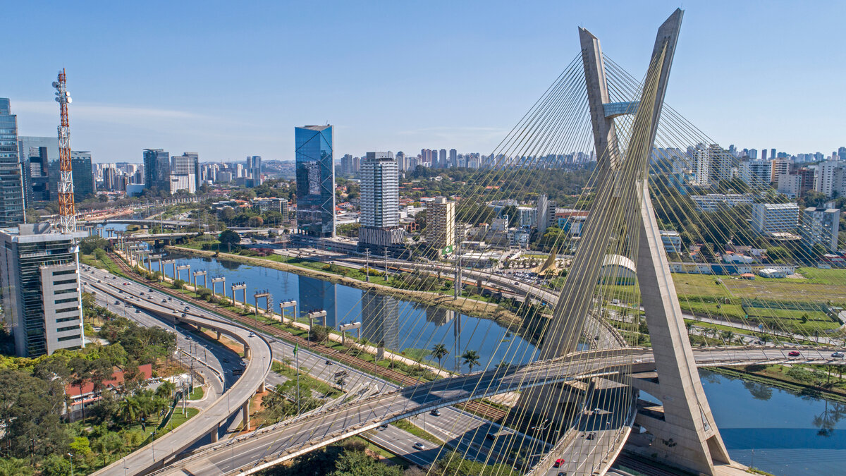 Luftaufnahme der Estaiada-Brücke in São Paulo mit ihren kreuzenden Straßen und dem Fluss Rio Pinheiros, umgeben von modernen Hochhäusern und breiten Verkehrsachsen bei klarem Himmel.