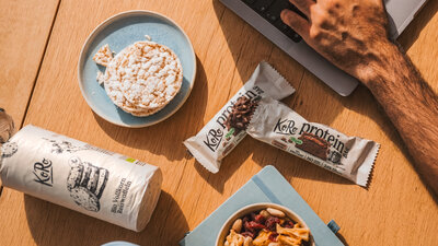 Schreibtisch mit Proteinriegeln und Produkten von KoRo. 