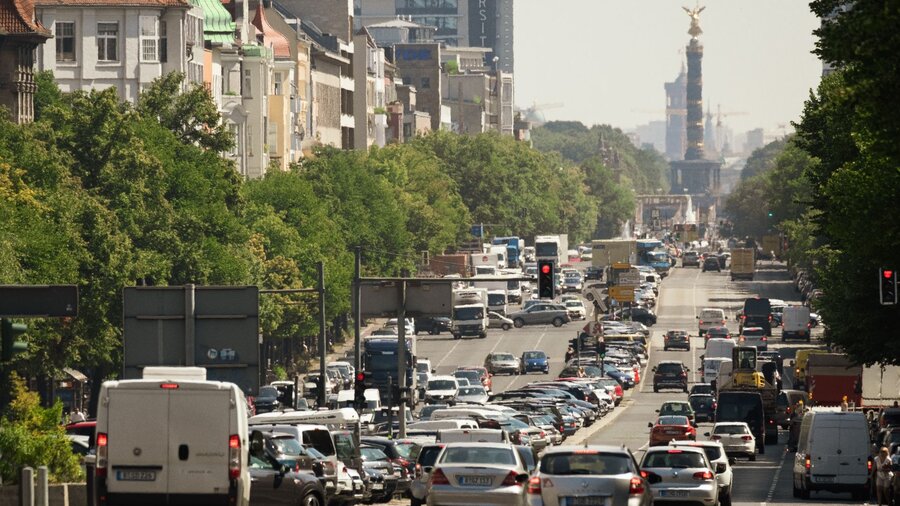 Zu sehen ist eine vielbefahrene Hauptstraße in einer Großstadt. Im Hintergrund ist die Siegessäule in Berlin zu erkennen.