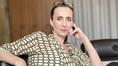 Zu sehen ist eine Frau in einem gemusterten Hemd, mit einer Lesebrille auf dem Kopf. Sie schaut neutral in die Kamera.