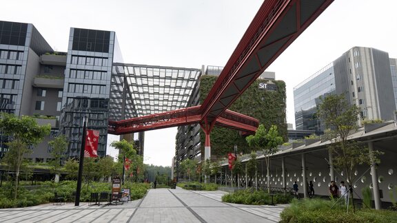 Eine moderne Stadt mit vielen Bäumen und grünflächen. In der Mitte verläuft eine rote Bahnschiene. 