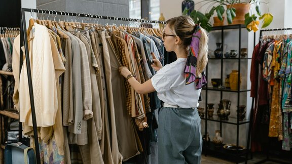 Eine junge Frau stöbert in einem Kleidungsgeschäft. 