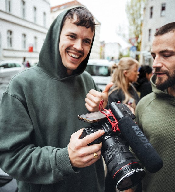 Alex Mundt von den KRAFT Runners hält eine Kamera und lacht