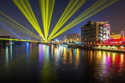 Foto von Berlin am Ufer mit mehreren Lichtern in der Nacht, welche in Richtung Kamera strahlen