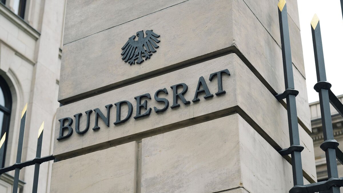 Zu sehen ist ein Ausschnitt eines Zaunes und eines Stein-Balkens, auf dem Bundesrat steht und das deutsche Wappentier, der Adler, zu sehen ist.
