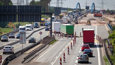 Zu sehen ist eine befahrene Autobahn. Auf einer Spur befindet sich eine Baustelle, weswegen eine Fahrbahn geteilt wurde, dort fahren die Fahrzeuge in beide Richtungen.