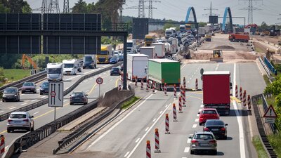 Zu sehen ist eine befahrene Autobahn. Auf einer Spur befindet sich eine Baustelle, weswegen eine Fahrbahn geteilt wurde, dort fahren die Fahrzeuge in beide Richtungen.