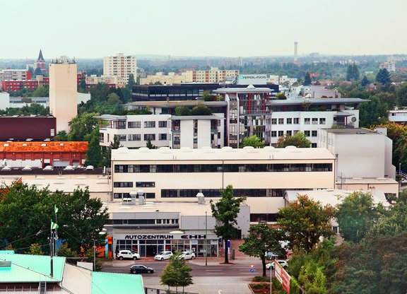 Blick auf mehrstöckige Büro- und Wohngebäude in einer Stadt mit Bäumen und Straßen im Vordergrund