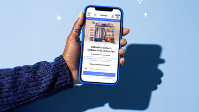 Ein Smartphone wird in einer Hand gehalten, darauf ist die Seite von Momox geöffnet.