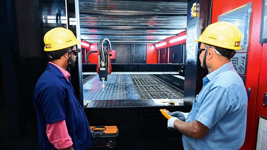 Zwei Männer in gelben Bauhelmen arbeiten an einer Schweißmaschine