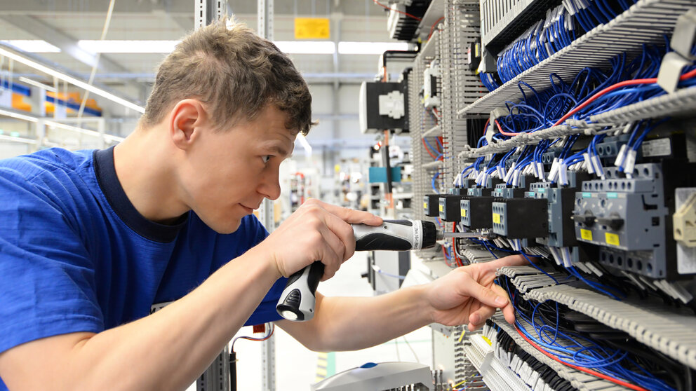 Azubi arbeitet an einem elektronischen Schaltkreis. 