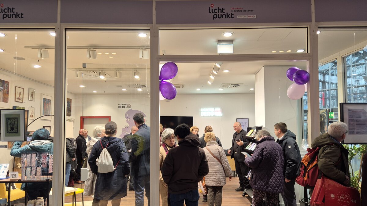 Ein hell beleuchtender Raum mit vielen Menschen, die sich stehend unterhalten. Es ist der Lichtpunkt im Allee-Center
