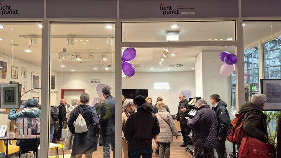 Ein hell beleuchtender Raum mit vielen Menschen, die sich stehend unterhalten. Es ist der Lichtpunkt im Allee-Center