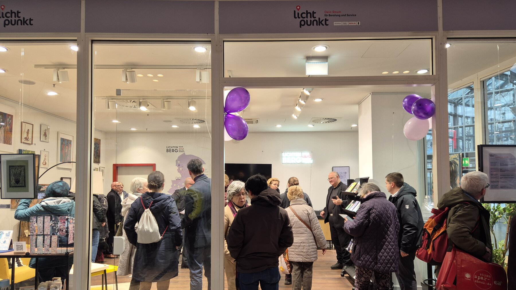 Ein hell beleuchtender Raum mit vielen Menschen, die sich stehend unterhalten. Es ist der Lichtpunkt im Allee-Center