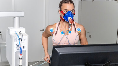 Frau, die während eines kardiopulmonalen Stresstests auf dem Laufband-Ergometer läuft.