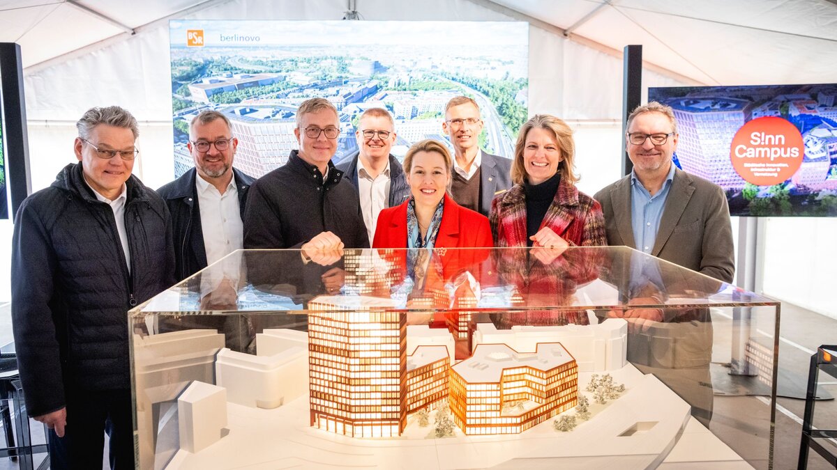 Zu sehen sind mehrere Personen, die in einem weißen Zelt stehen und freundlich für ein Gruppenfoto in die Kamera blicken. Es handelt sich um die Teilnehmenden einer Spatenstichveranstaltung der Berliner Stadtreinigungsbetriebe.