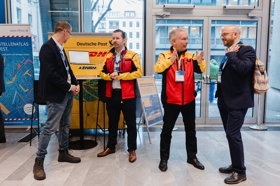 Zwei DHL-Vertreter im Gespräch mit zwei Männern auf einem Kongress.