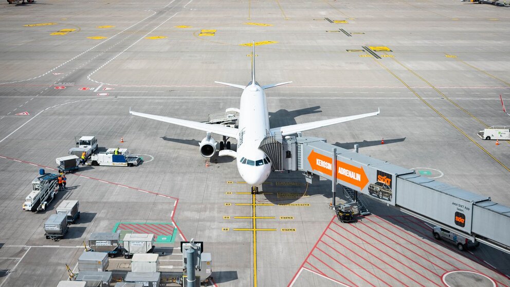 Zu sehen ist ein Passagierflugzeug, welches durch einen Gang mit dem Terminal verbunden ist, damit die Menschen zu- oder aussteigen können. Es handelt sich um eine Szene auf dem Flughafen BER in Berlin.