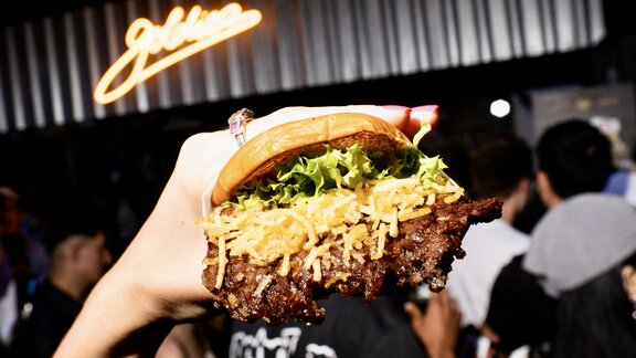 Ein Goldies-Smashburger, von einer Hand in die Kamera gehalten.