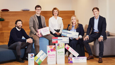 Das Dr. Kade Team posiert vor seinen Produkten. 