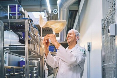 Foto eines Kochs mit einem Pizzateig