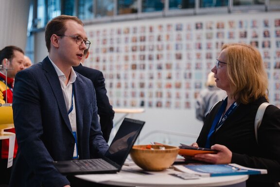 Ein Mann im Sakko unterhält sich an einem Stehtisch mit einer Frau.